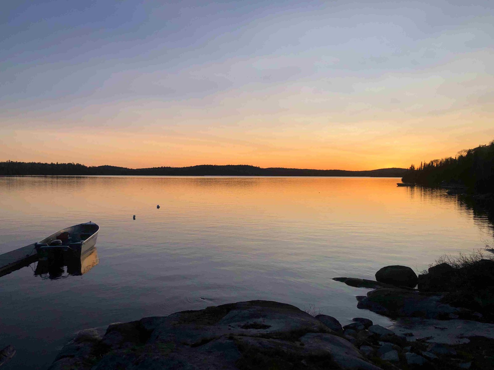 Sunset over Dog Lake with boat tied at the Northern Walleye Lodge dock, Missanabie